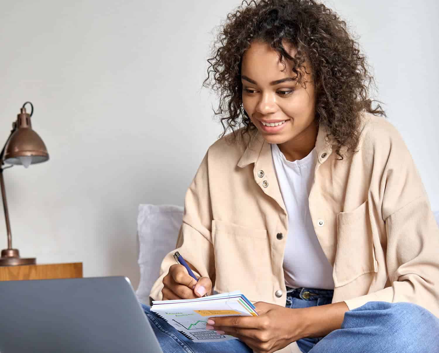 Young woman working on laptop and taking notes.